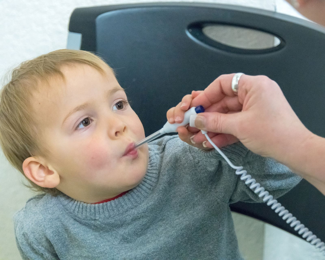 Child getting a temperature check with an oral thermometer in a medical setting.