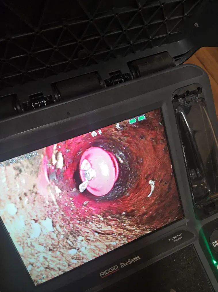 Endoscopic view inside a red-brown tube, with a pink circular opening at the center on a device screen