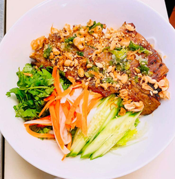 Plate of stir-fried noodles with chicken and vegetables on a wooden table