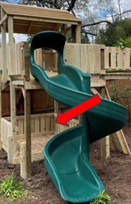 Green spiral slide attached to a wooden playset, with a red arrow pointing to a damaged section underneath