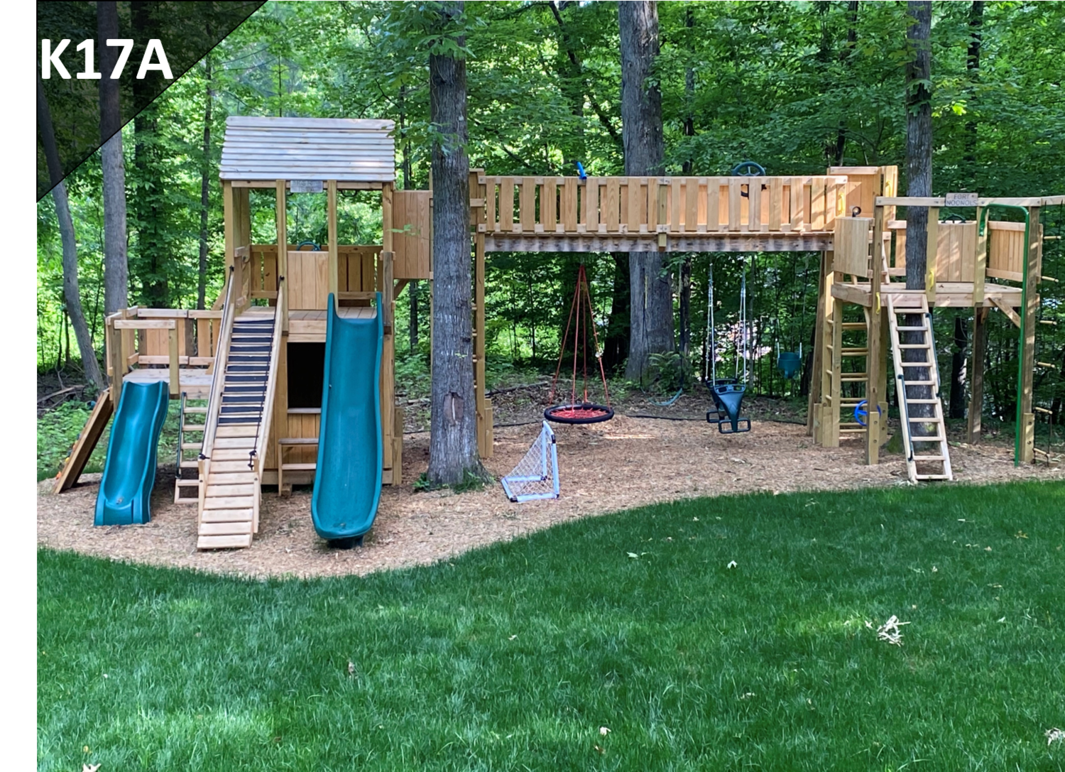 Backyard wooden playground with slides, ladders, and a raised deck among trees