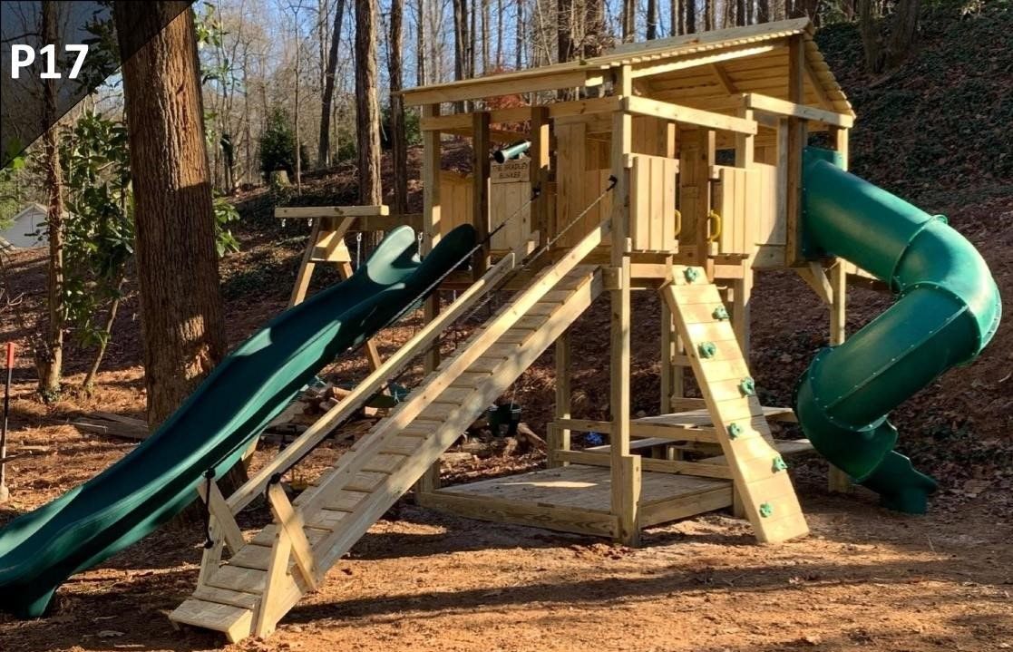 Wooden playground fort with dual slides and stairs in a wooded park area