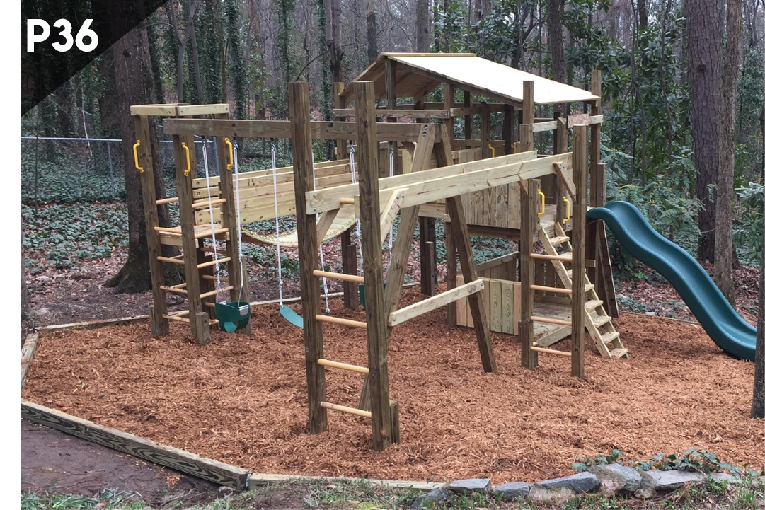 Wooden playground structure with blue slide in a wooded park, covered in mulch.