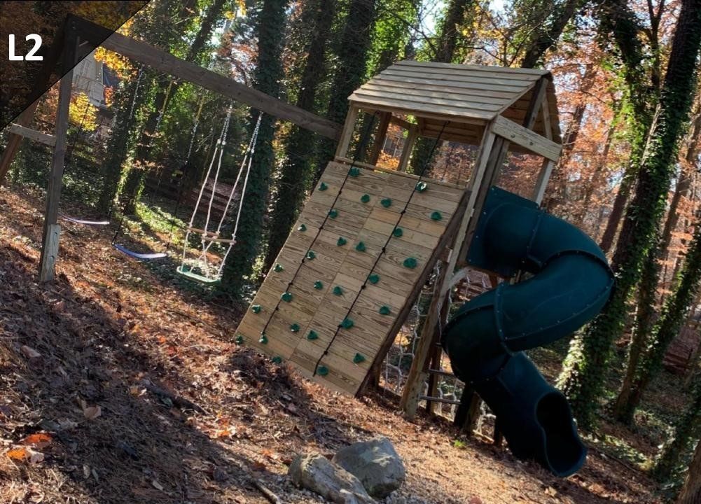 Person climbing a wooden obstacle wall in a wooded outdoor course