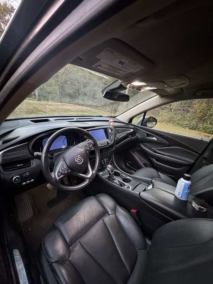 The interior of a Buick car features black leather seats, a dashboard with a touchscreen, and a steering wheel with a logo.