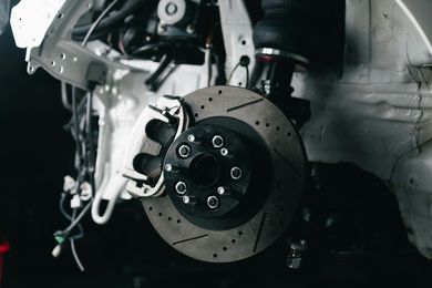 A close-up view of a car's brake rotor and wheel hub assembly mounted on the vehicle's suspension system.
