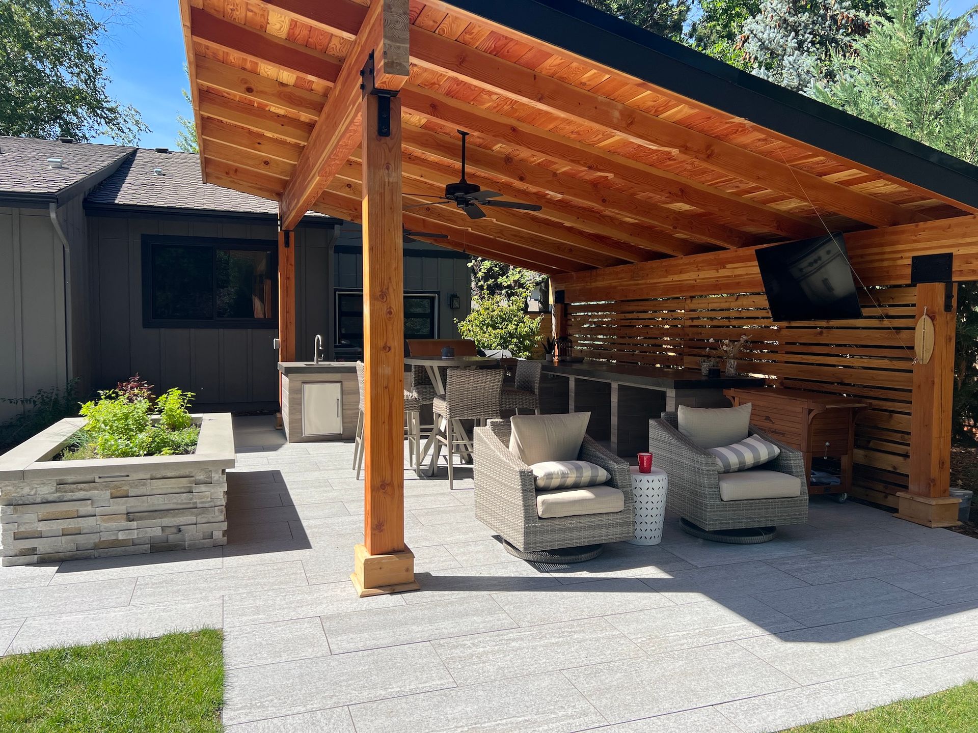 A patio with chairs and a table under a wooden roof