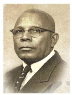 Studio portrait of a man in glasses and a suit against a plain background