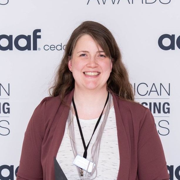 A woman is smiling in front of a wall that says aaf