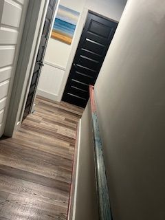 A person in a blue cap paints a wall blue with a roller. White paint is visible on the left side of the wall.