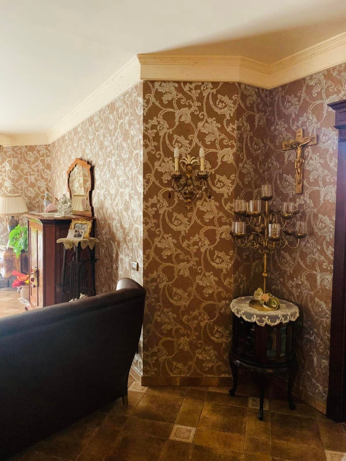 Elegante soggiorno con carta da parati a motivi marroni, applique, tavolino e specchio.