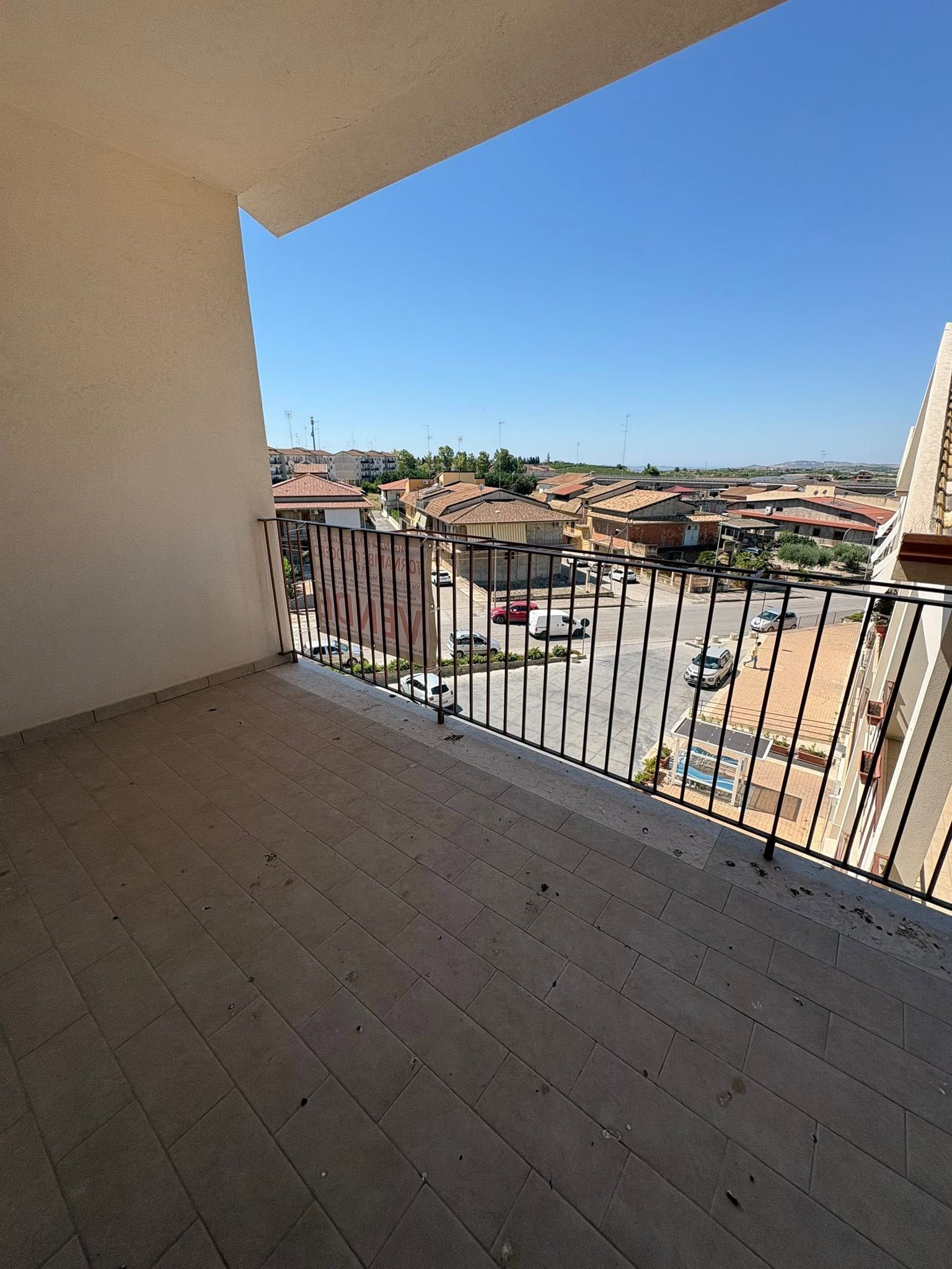 Balcone coperto con vista su un paesaggio urbano piastrellato sotto un cielo azzurro limpido.