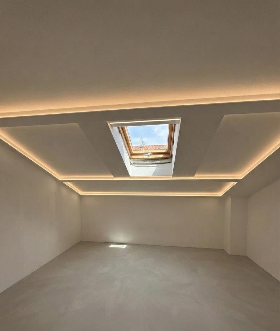 Stanza bianca vuota con faretti a incasso sul soffitto e un lucernario che si apre sopra