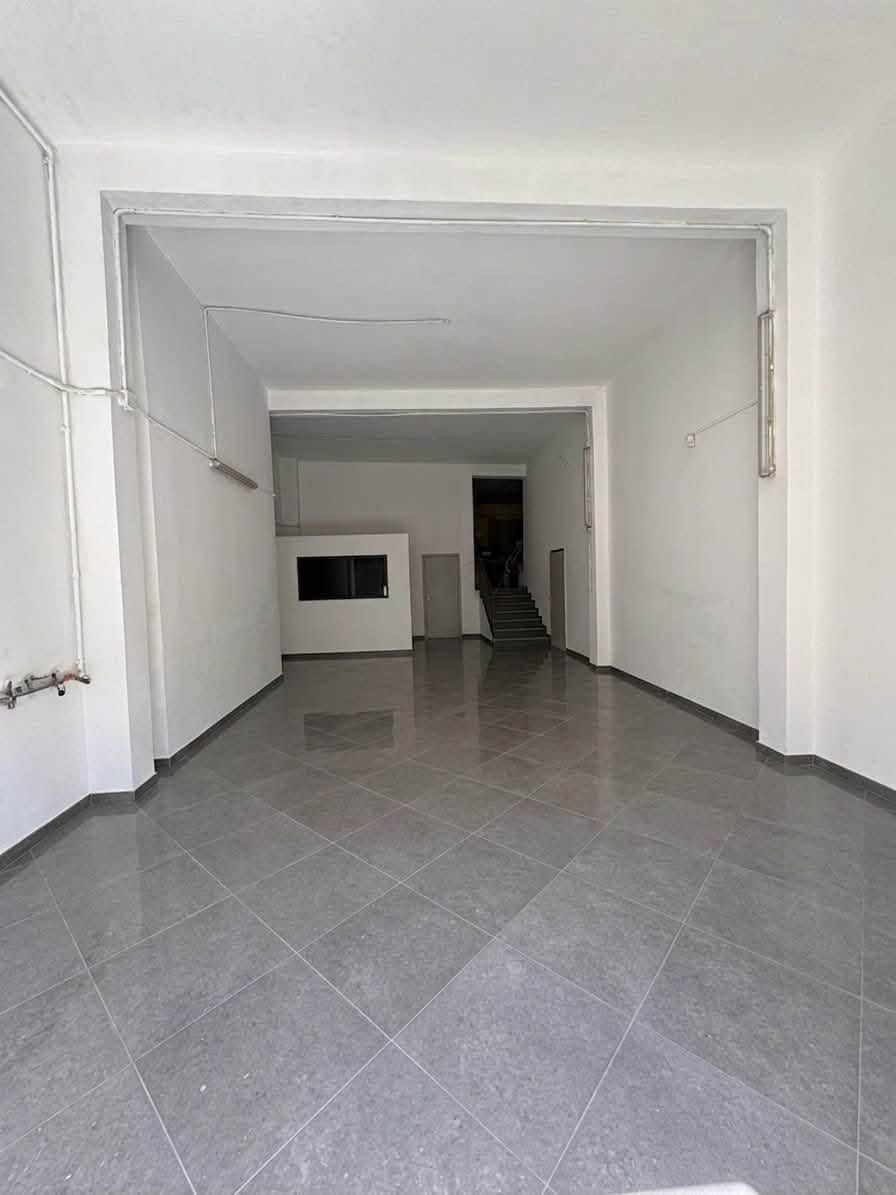 Stanza bianca vuota con pavimento piastrellato di grigio e una porta in lontananza.