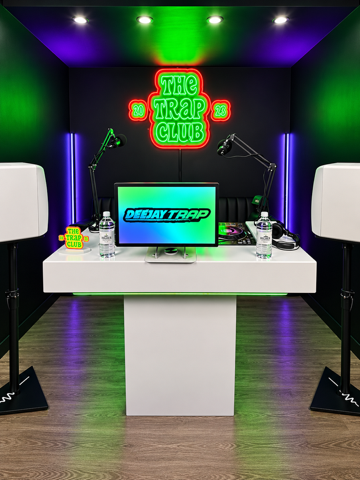 Smiling man wearing glasses and jewelry, resting his hand on his forehead inside a car.