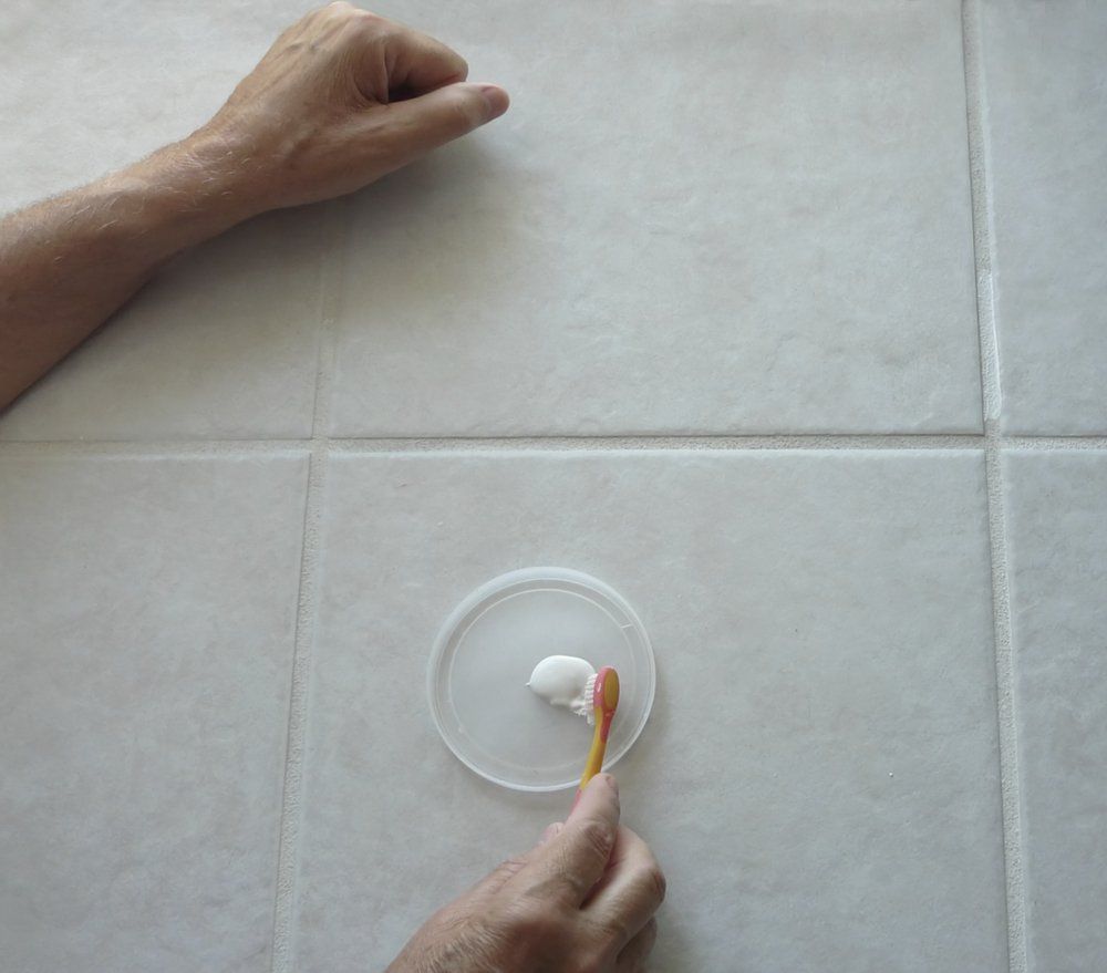 A Person Is Using A Tooth Brush To Clean A Tiled Floor — Turbo Clean in Taree, NSW