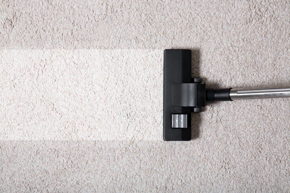 A Vacuum Cleaner Is Cleaning a White Carpet — Turbo Clean in Taree, NSW