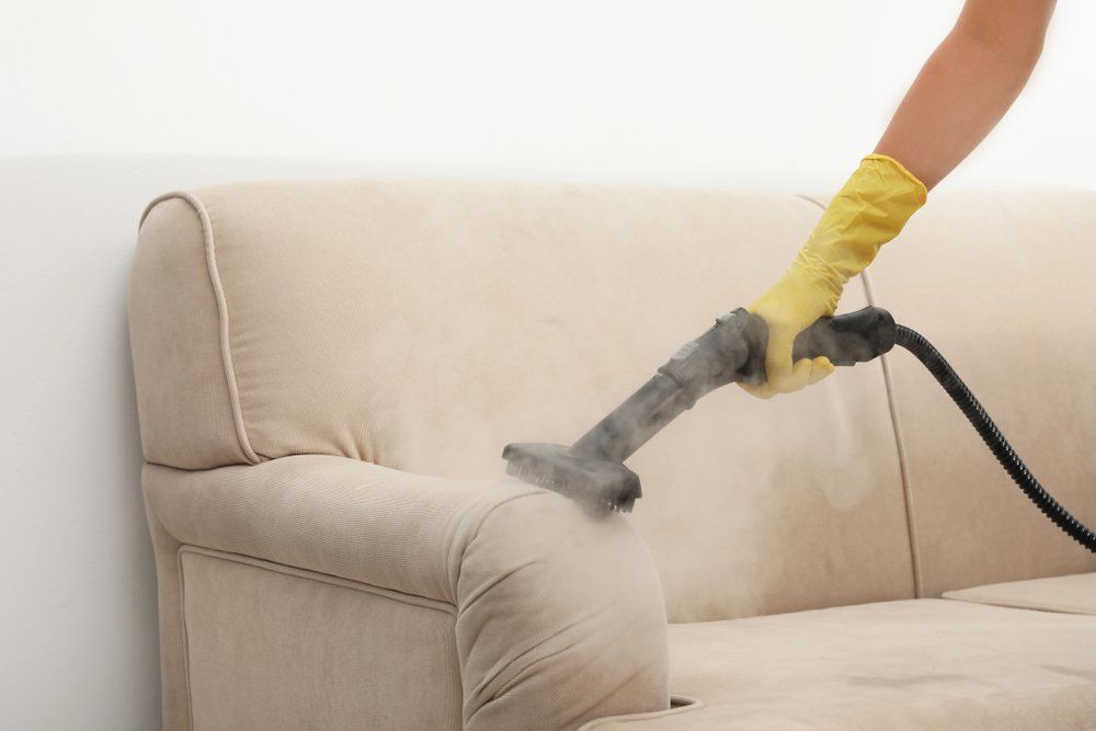 A Person Is Cleaning a Couch with A Vacuum Cleaner — Turbo Clean in Tuncurry, NSW