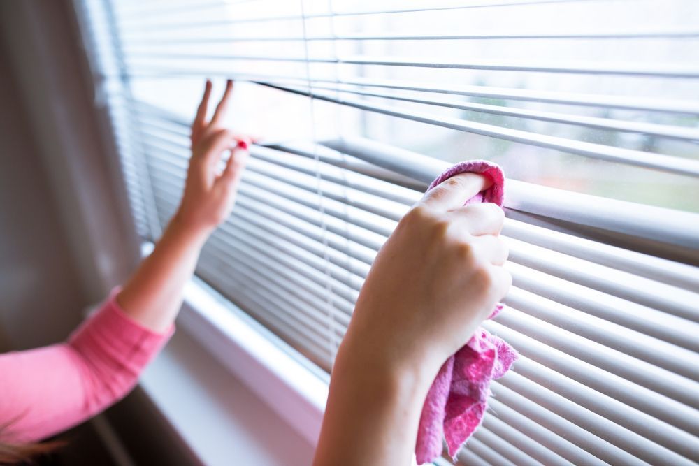 A Woman Is Cleaning Blinds with A Cloth — Turbo Clean in Tuncurry, NSW