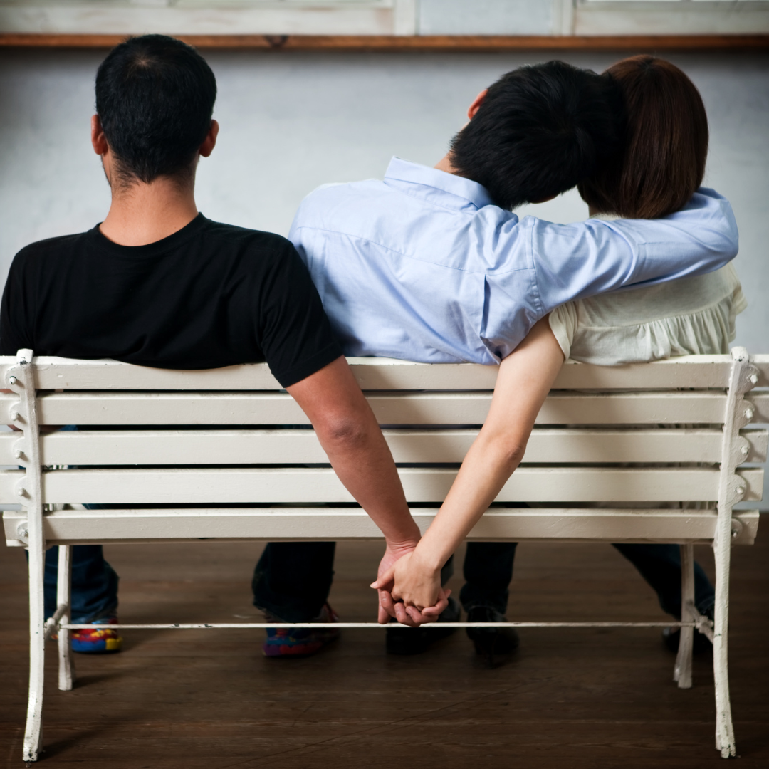 A man and a woman are sitting on a bench holding hands