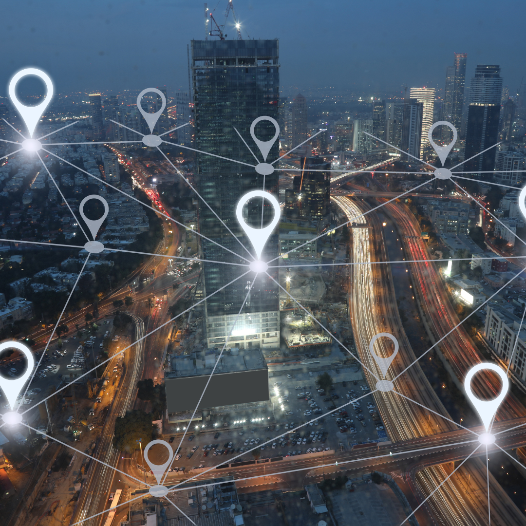 An aerial view of a city at night with a network of pins connected to each other.