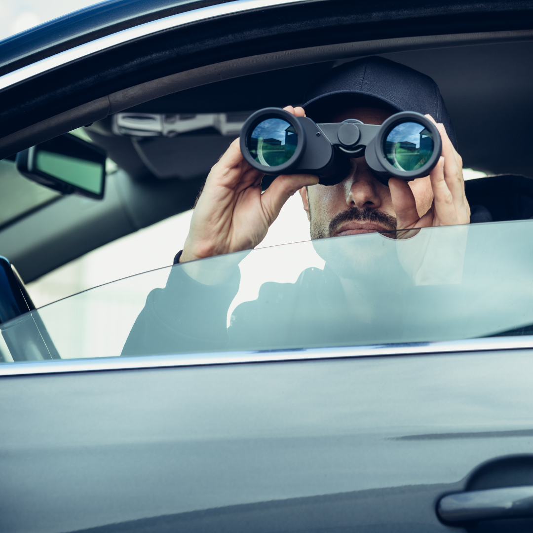 A man in a car is looking through binoculars