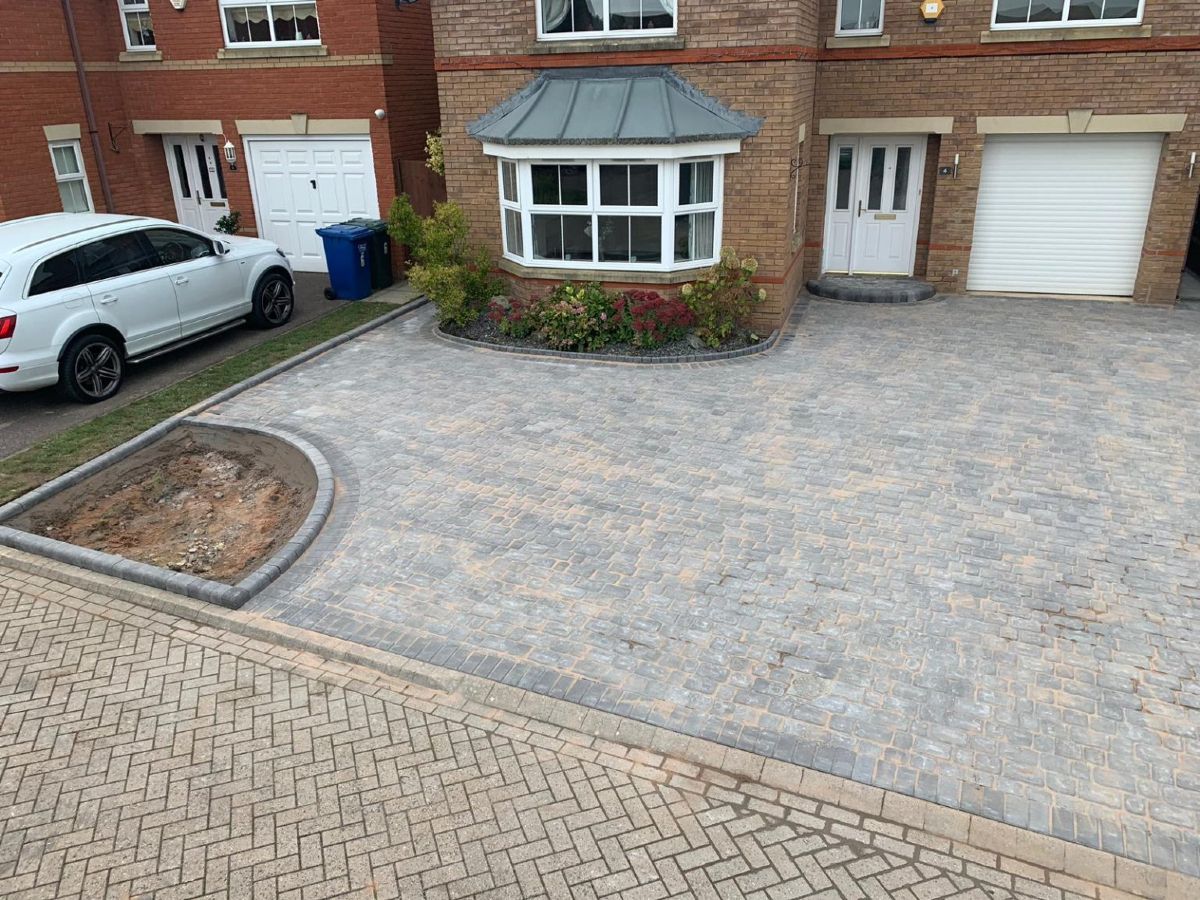Brick house front with paved driveway, white car, bay window, and garage door