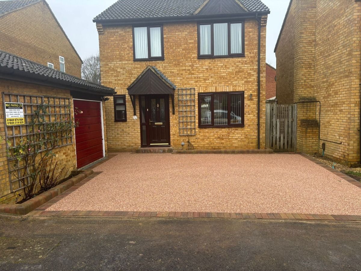 Brick house with a red gravel driveway and garage on the left