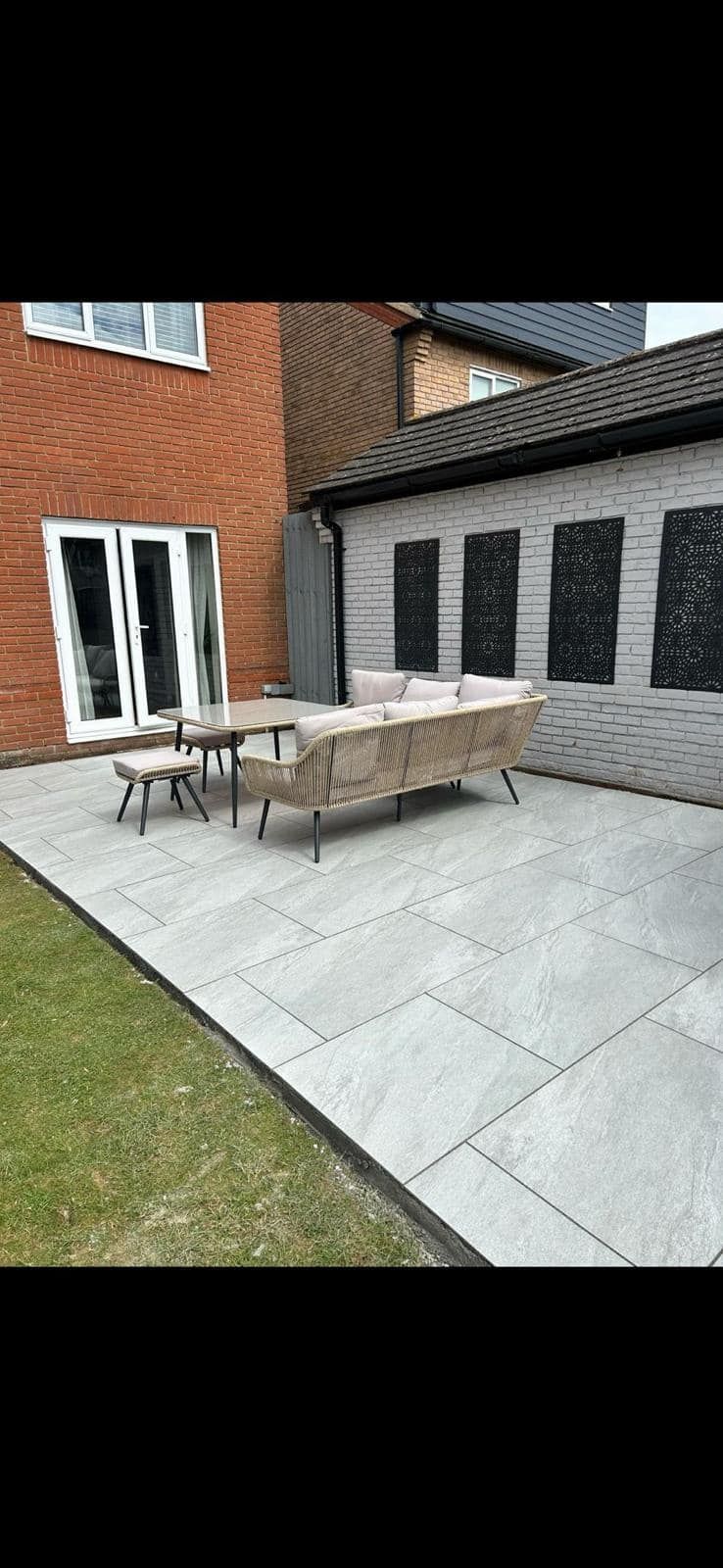Patio with outdoor table and chairs beside a brick house and black garage doors
