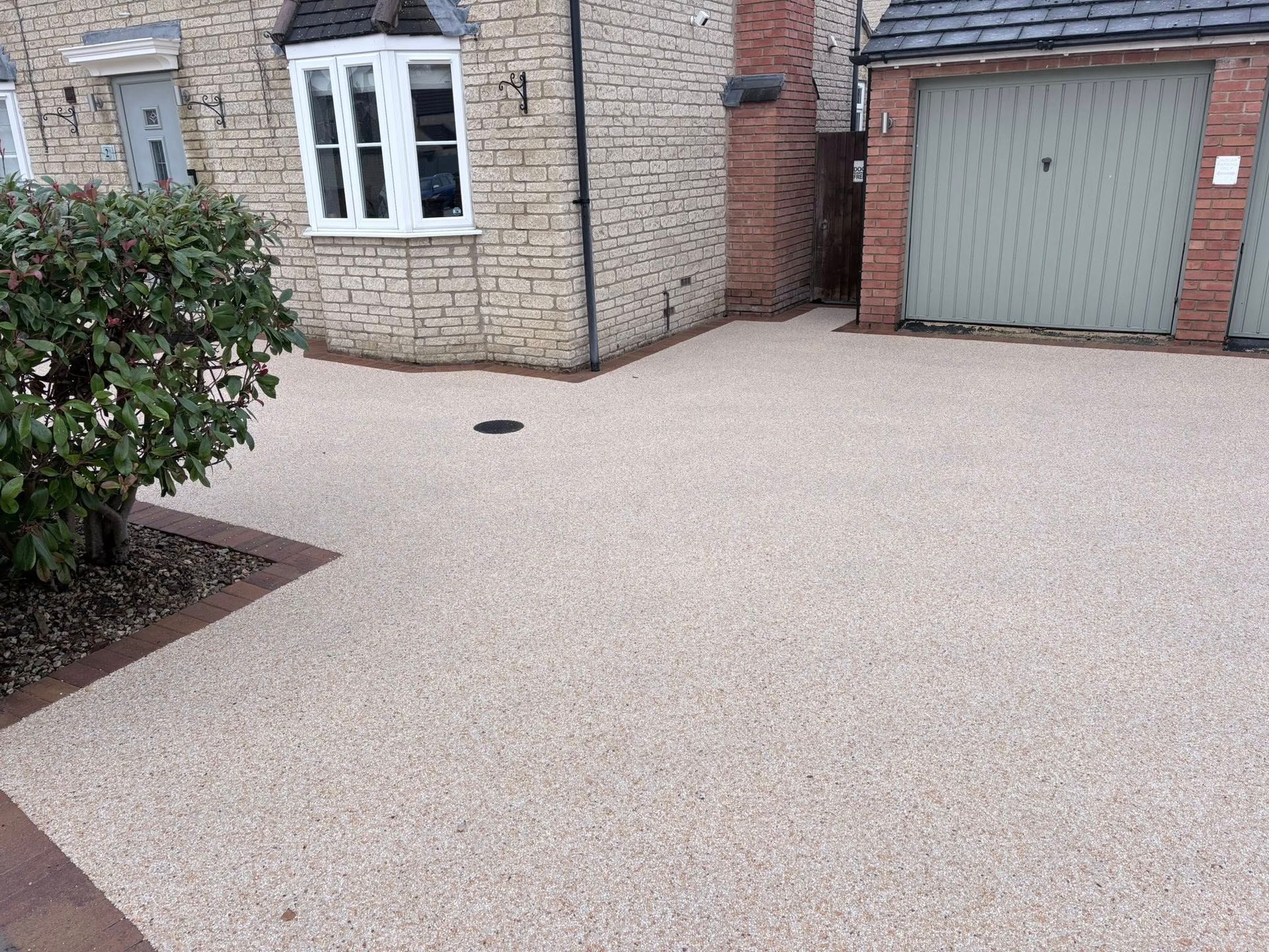 Gravel driveway beside a brick house with a garage and white-framed windows.
