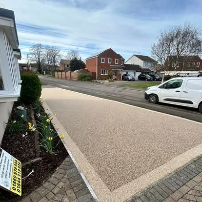 Completed light-coloured residential driveway with contrasting block paving at the entrance.