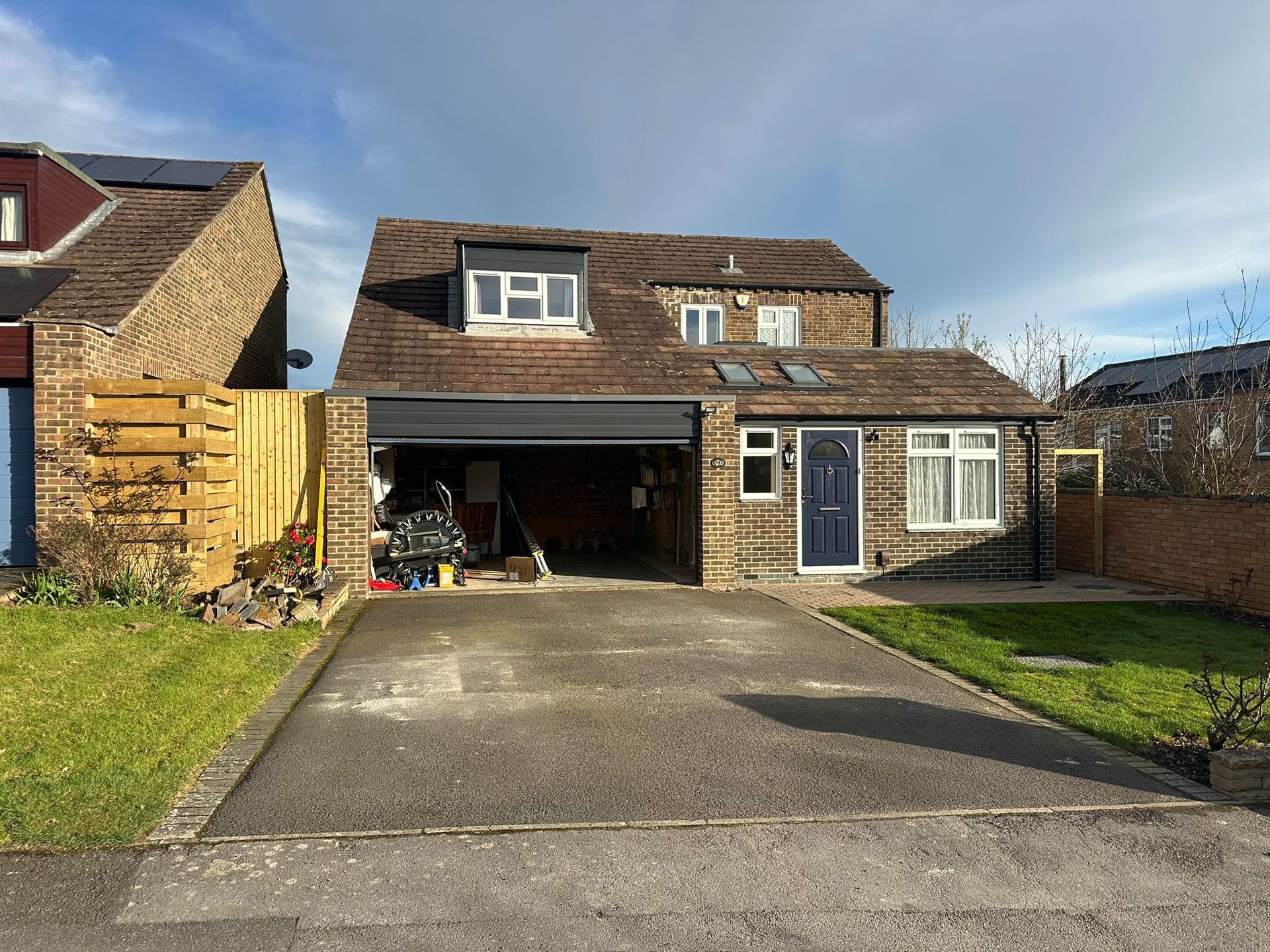 Suburban house with a driveway and open garage, seen from the street on a sunny day