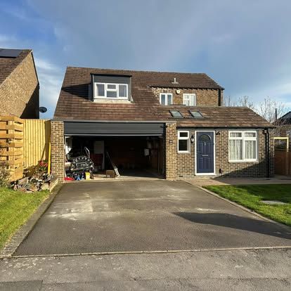Suburban house with a driveway, open garage, blue front door, and small front lawn