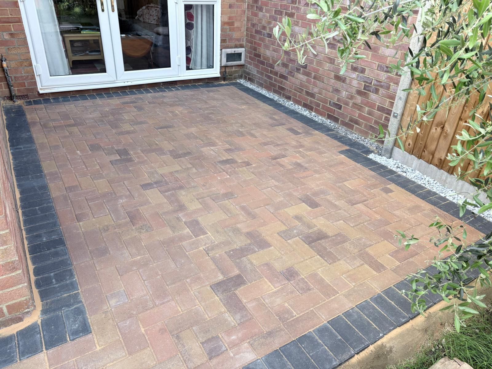 Stone patio steps leading to a glass conservatory beside a rustic house and garden