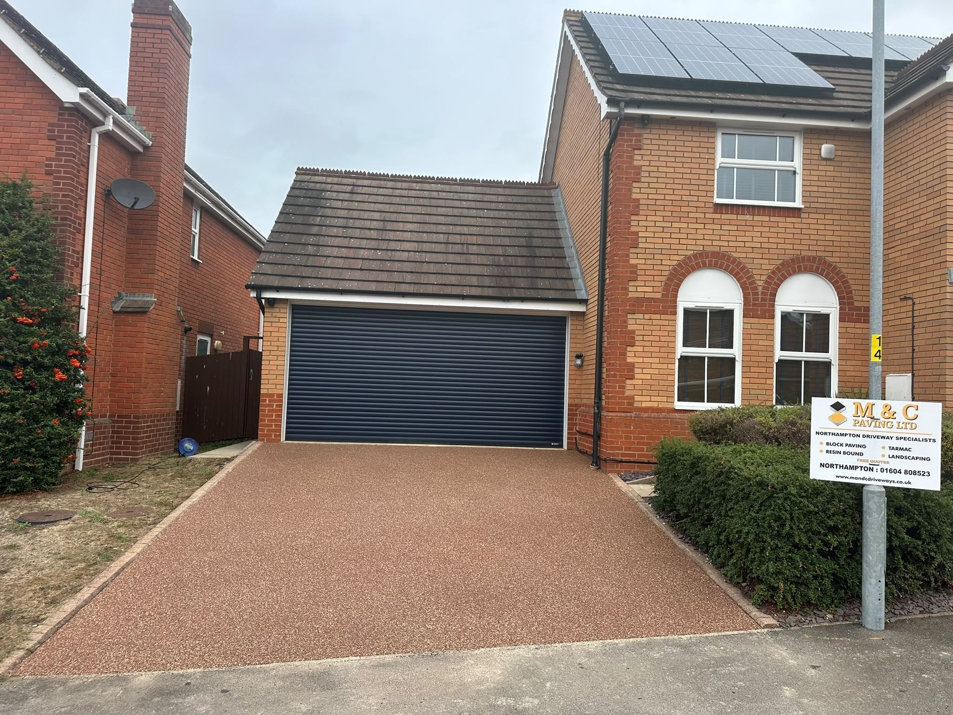 Brick house driveway with a closed garage door and solar panels on the roof