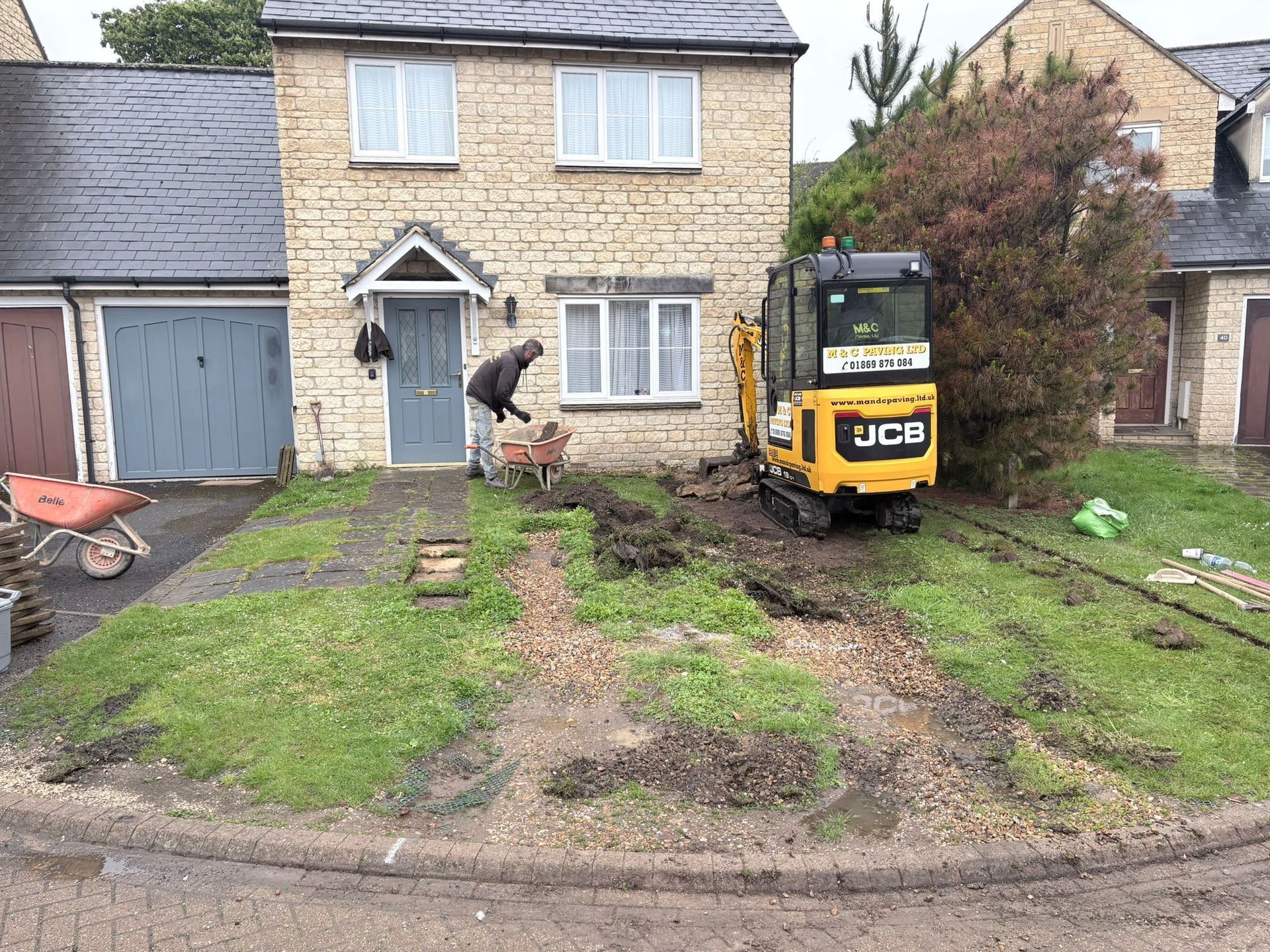 Residential driveway with wooden fence, gravel edges, and a garage in the background.