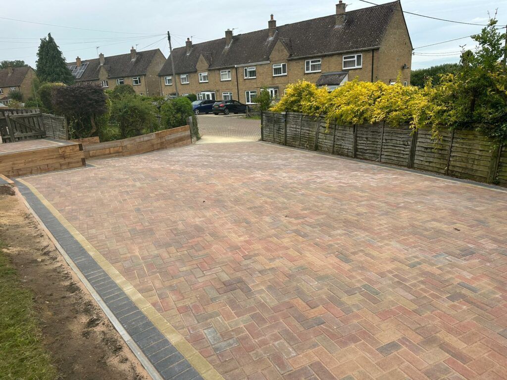 Brick-paved driveway leading to stone houses and hedges in a quiet residential street