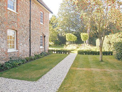 Landscaped garden with gravel pathway beside a traditional brick house