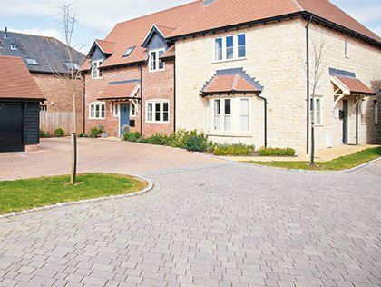 Modern suburban brick houses with a paved driveway and small lawn on a sunny day