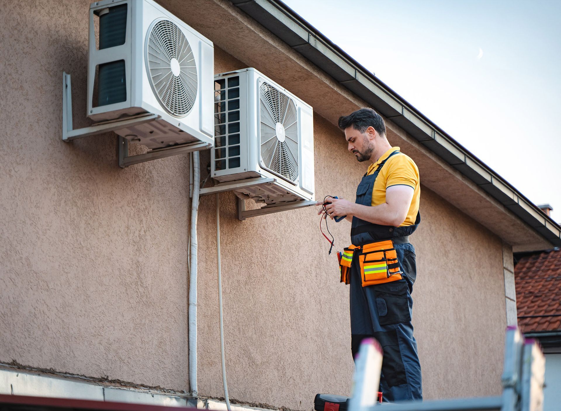HVAC technician on a ladder, inspecting AC units mounted on a building's exterior.