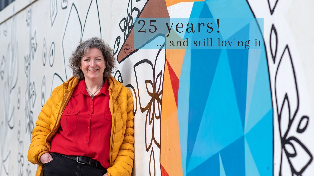 Alison Randle leaning against a large graffiti kingfisher, looking happy