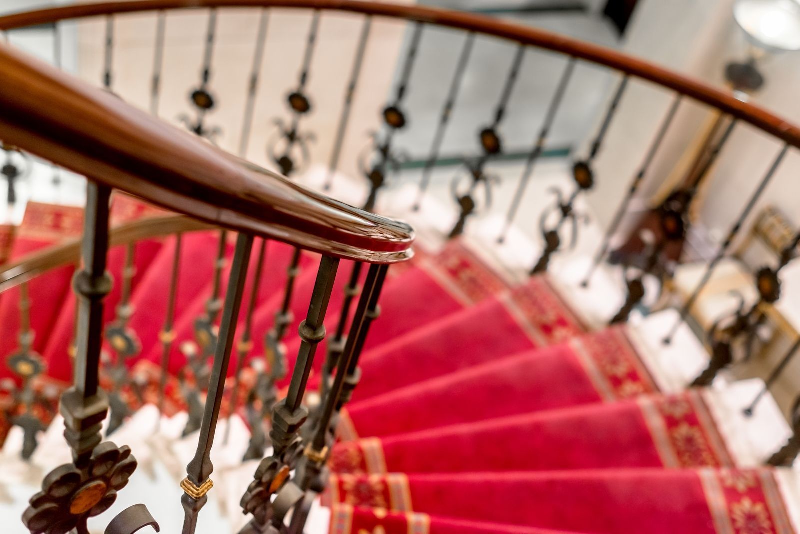 A staircase with a red carpet and a wrought iron railing