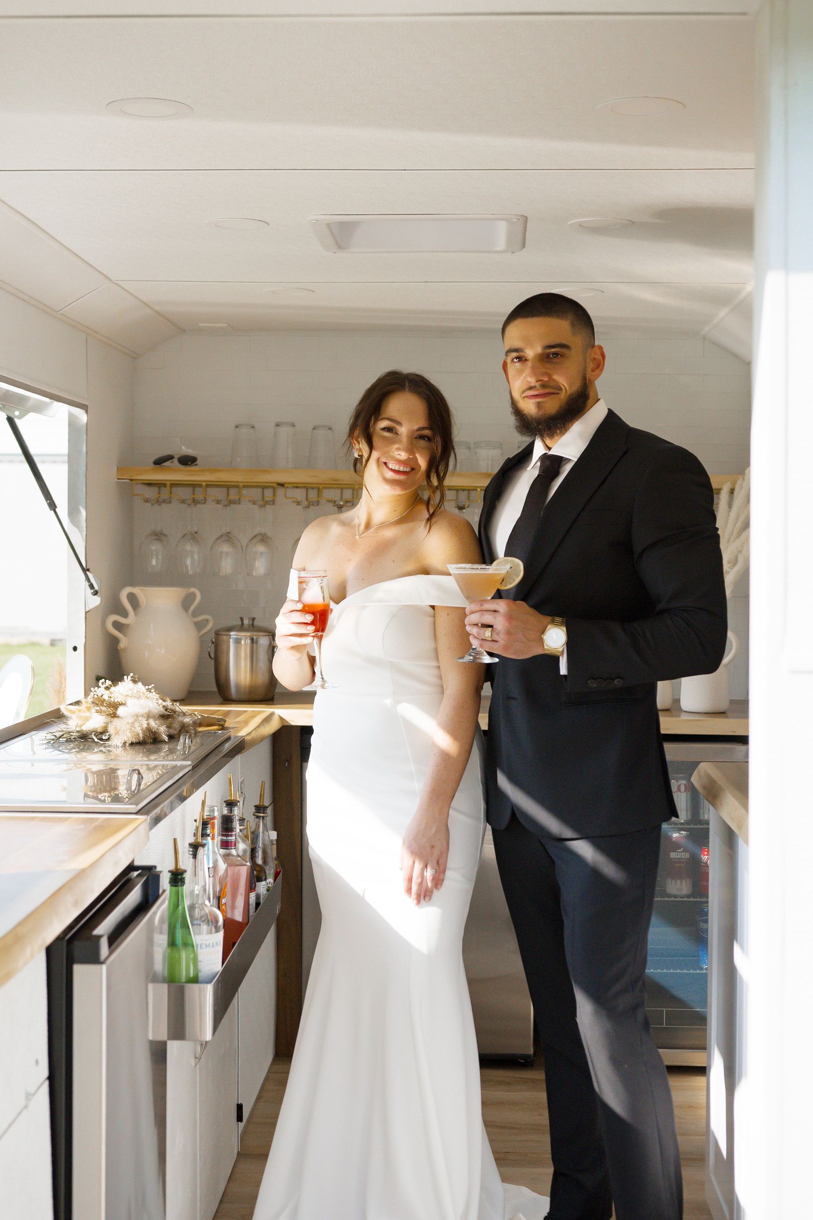 A couple standing inside The Cocktail Cart holding drinks