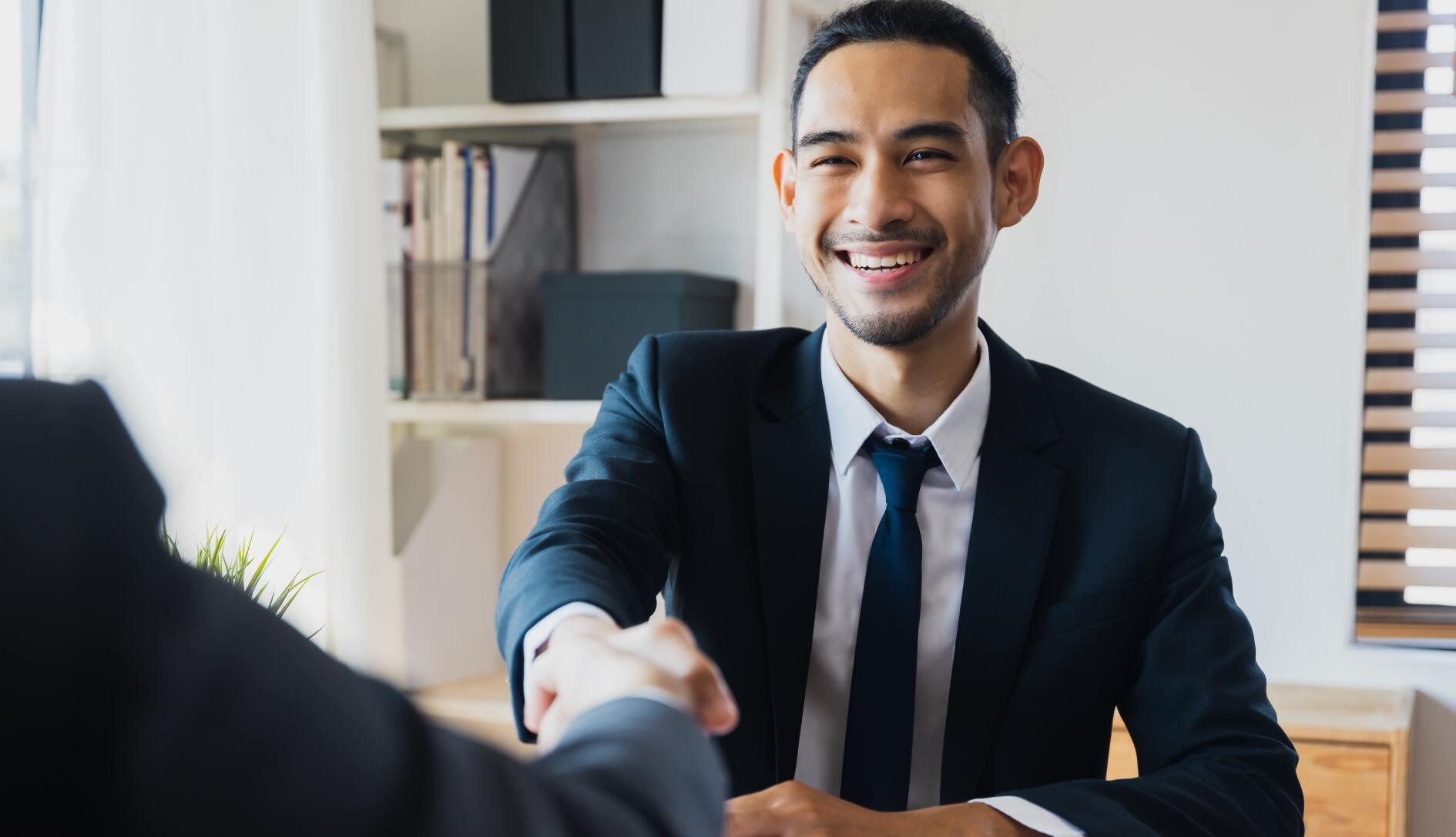 Man smiling and shaking a persons hand