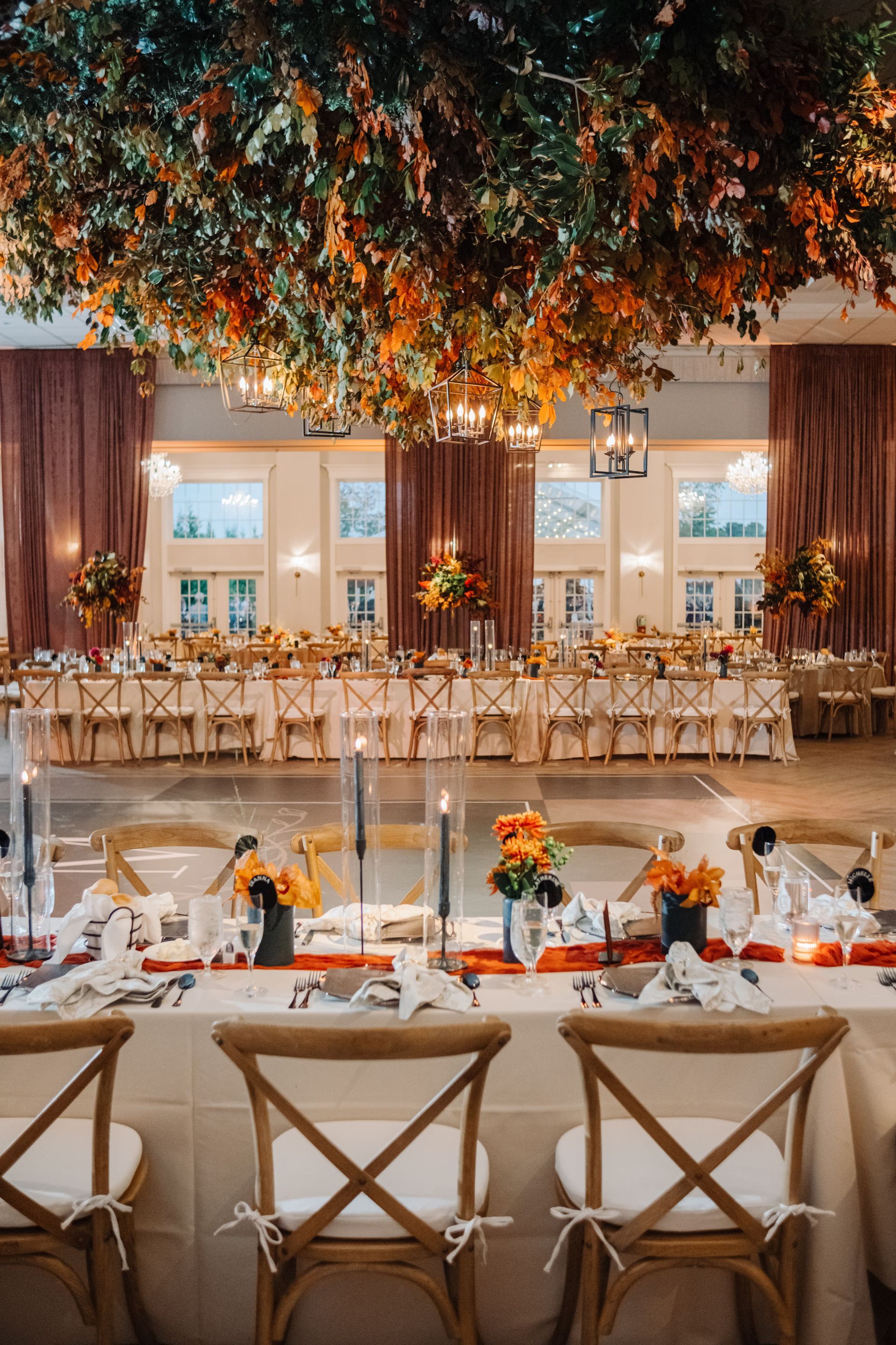 Elegant wedding reception hall with long candlelit tables and a floral ceiling centerpiece