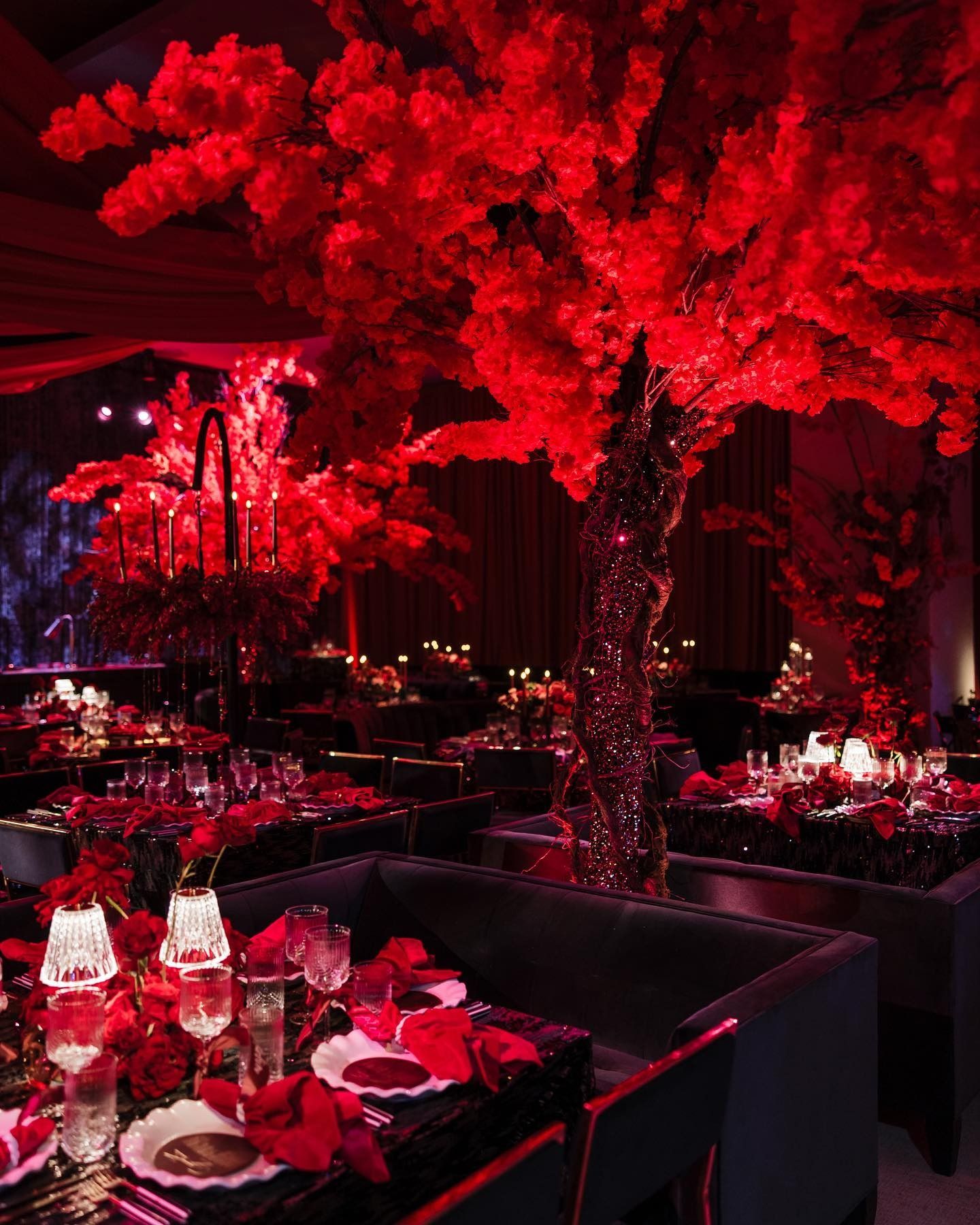 Red-lit banquet room with glowing red tree centerpiece and elegant dining tables set for an event