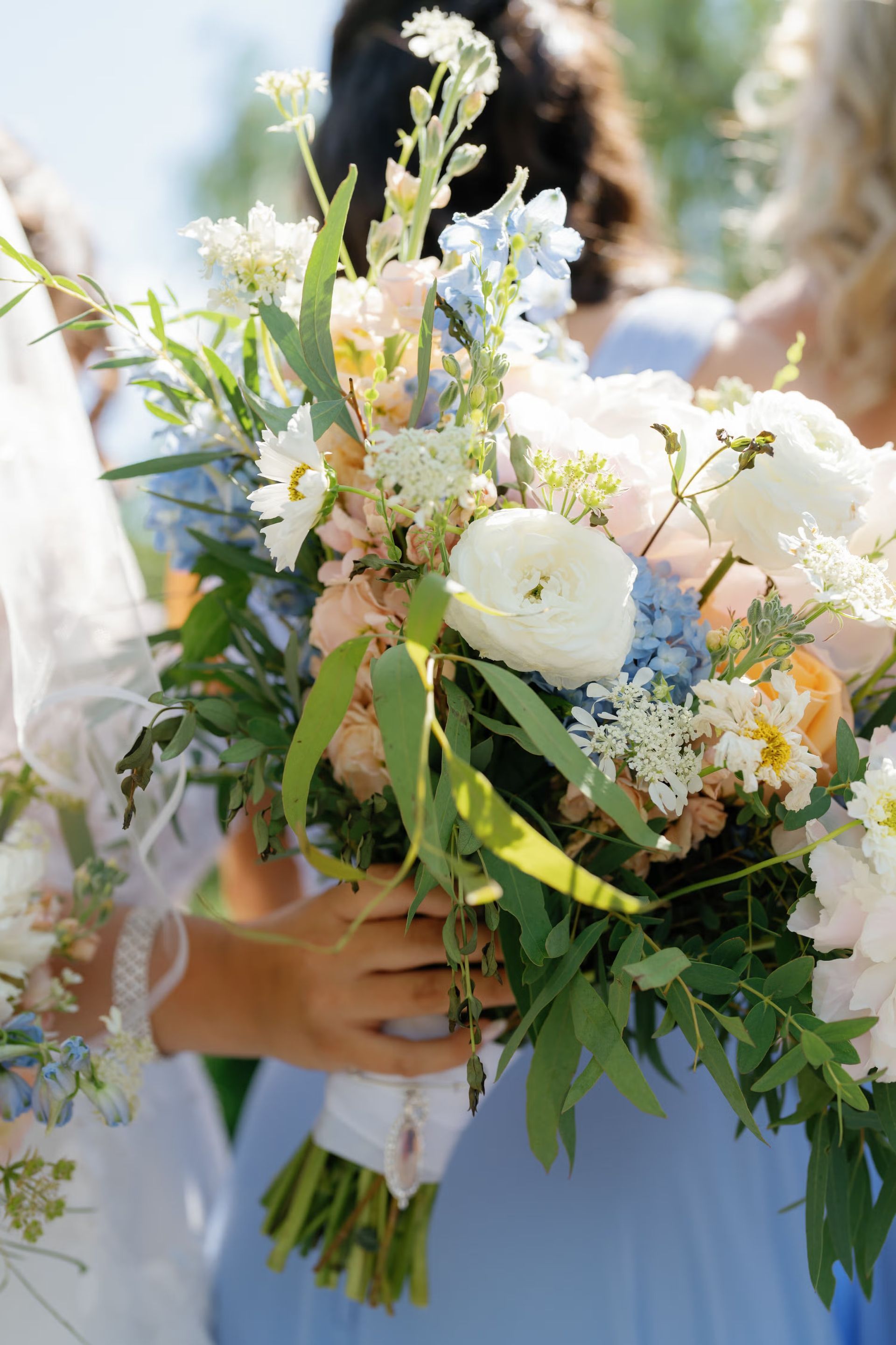 Bride holding a pastel bouquet of white, blue, and peach flowers