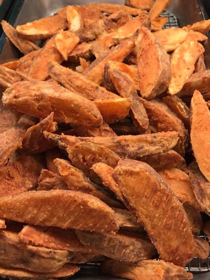 Close-up of seasoned sweet potato fries piled together, golden-brown and crispy.