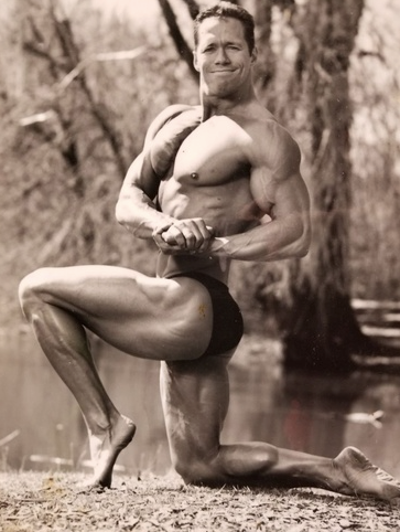 A black and white photo of a bodybuilder posing for a picture.