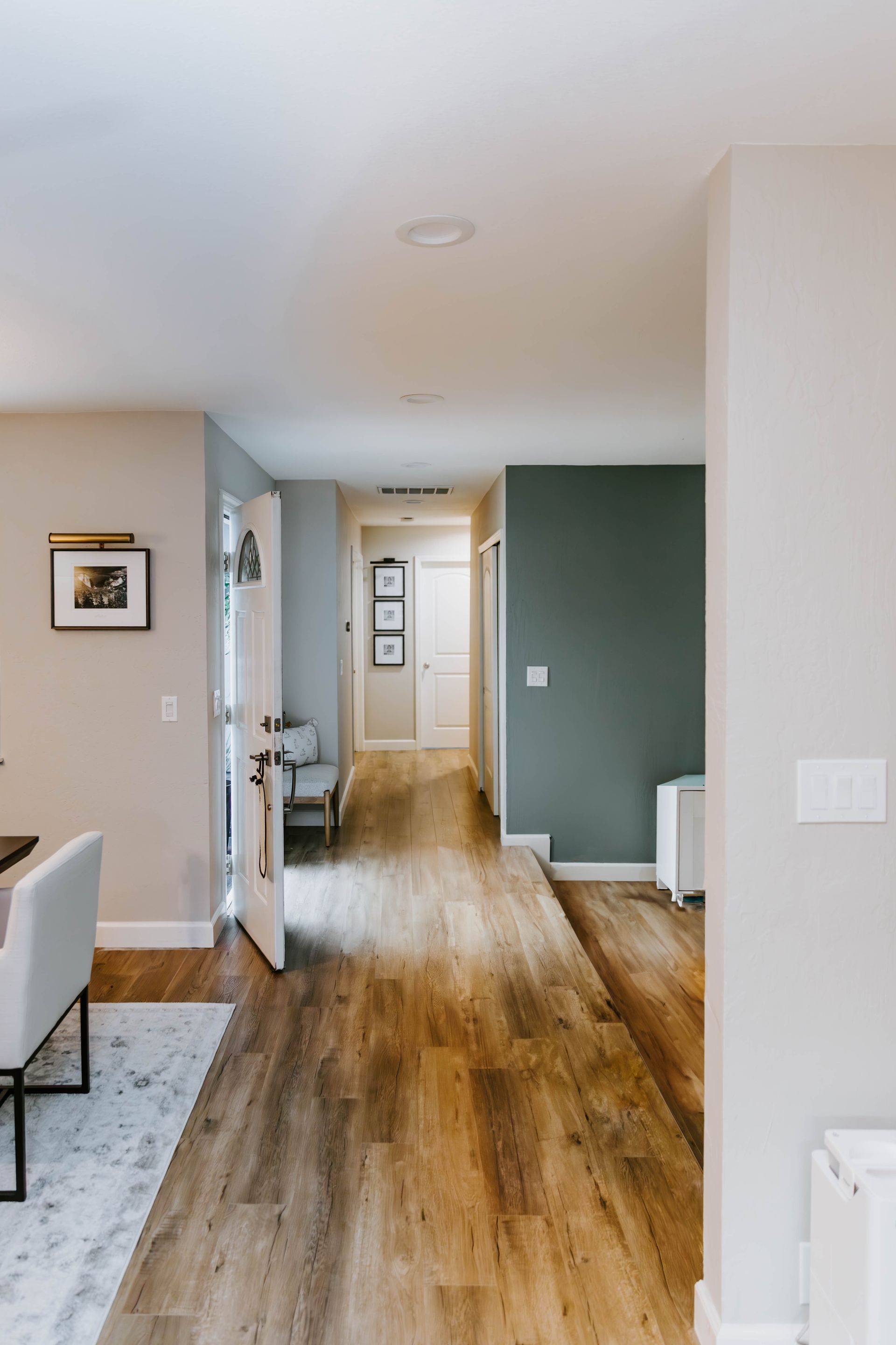 Hallway with wood floors, neutral walls, and a green accent wall.